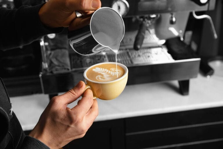 close up hand pouring milk delicious coffee cup 3 768x512